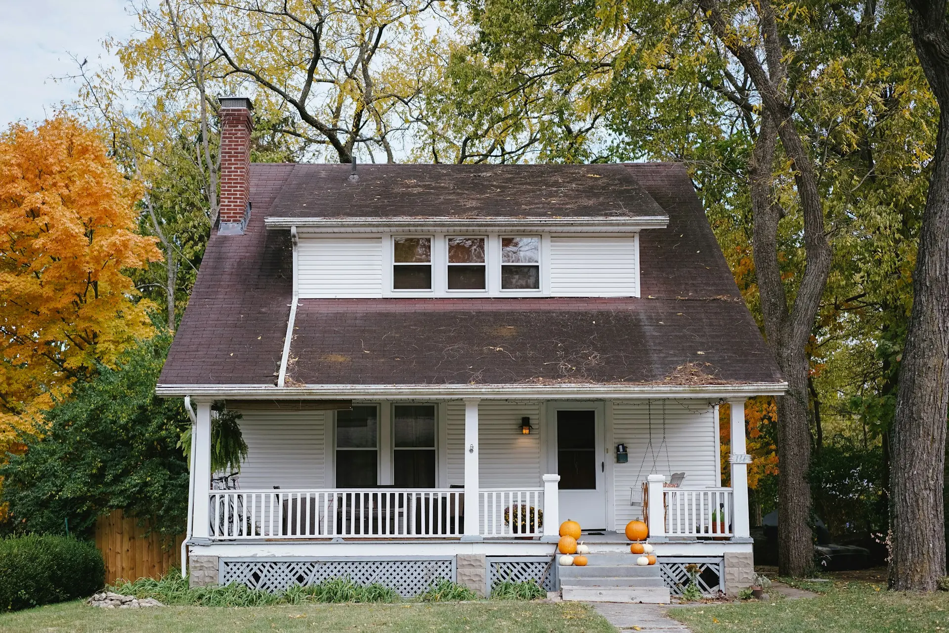 Casa de dos pisos con porche y árboles de otoño