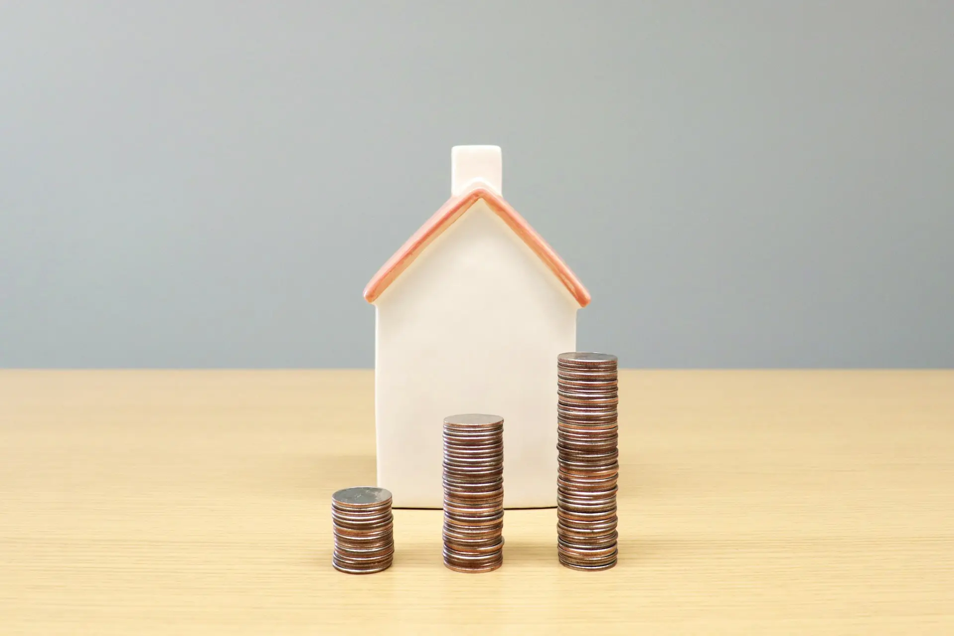 Una casita junto a tres pilas de monedas de distinto tamaño