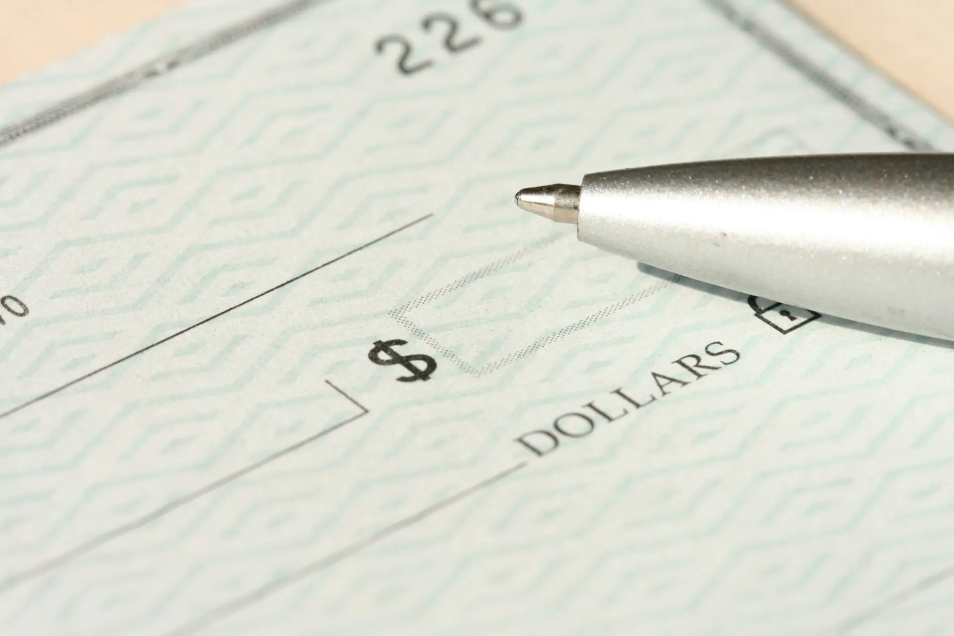 Un cheque en blanco con el signo de dólar y una pluma
