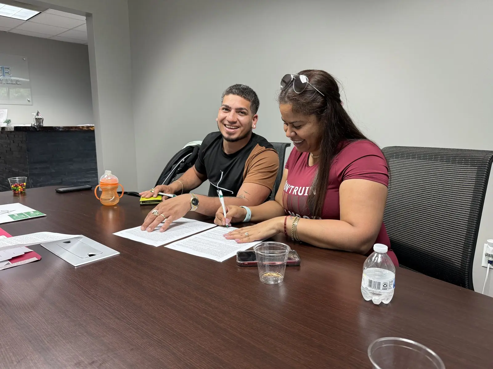 Una pareja firmando los papeles de su casa en la mesa de una oficina
