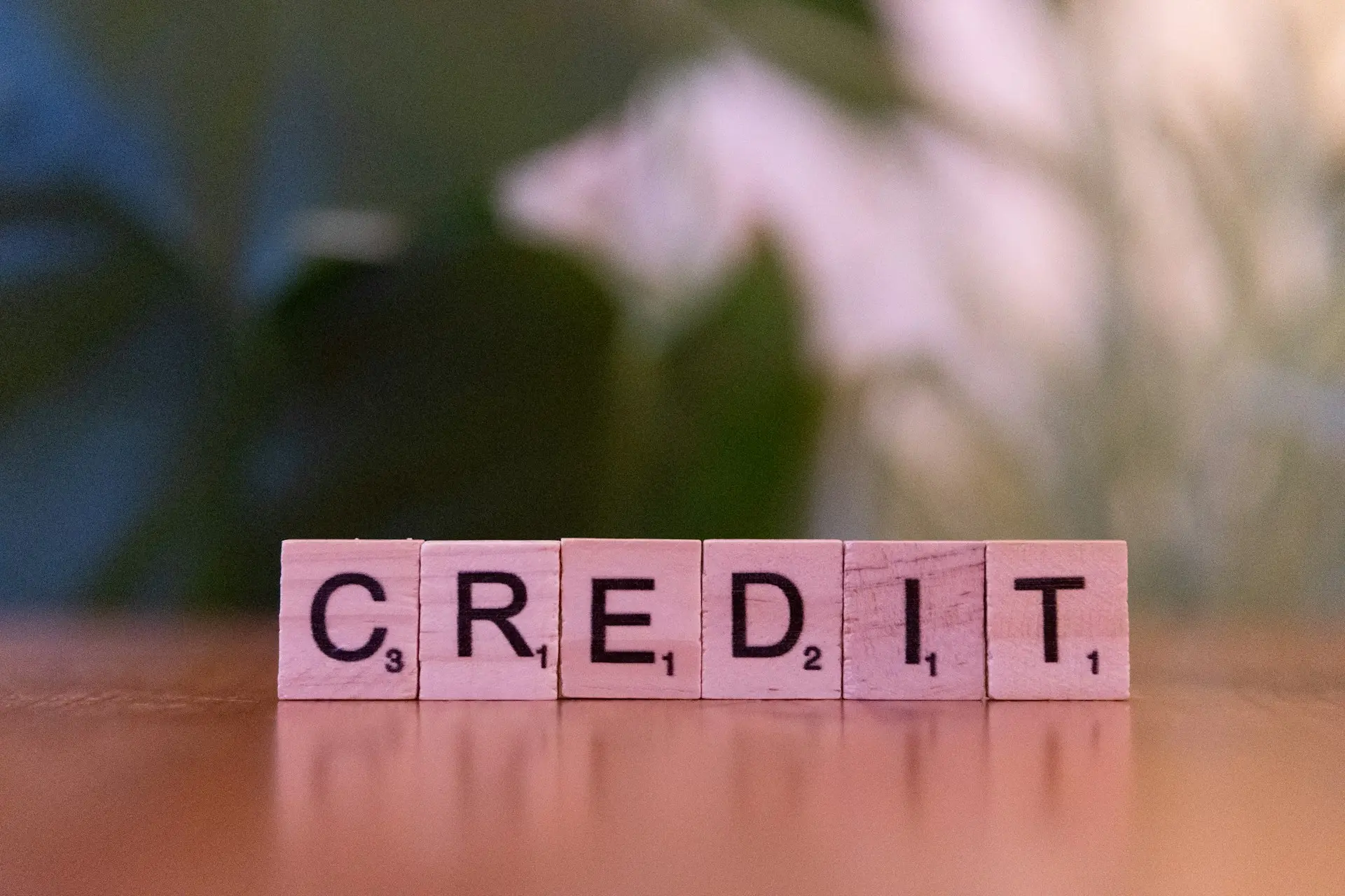 Letras de madera que forman la palabra «credit» sobre una mesa
