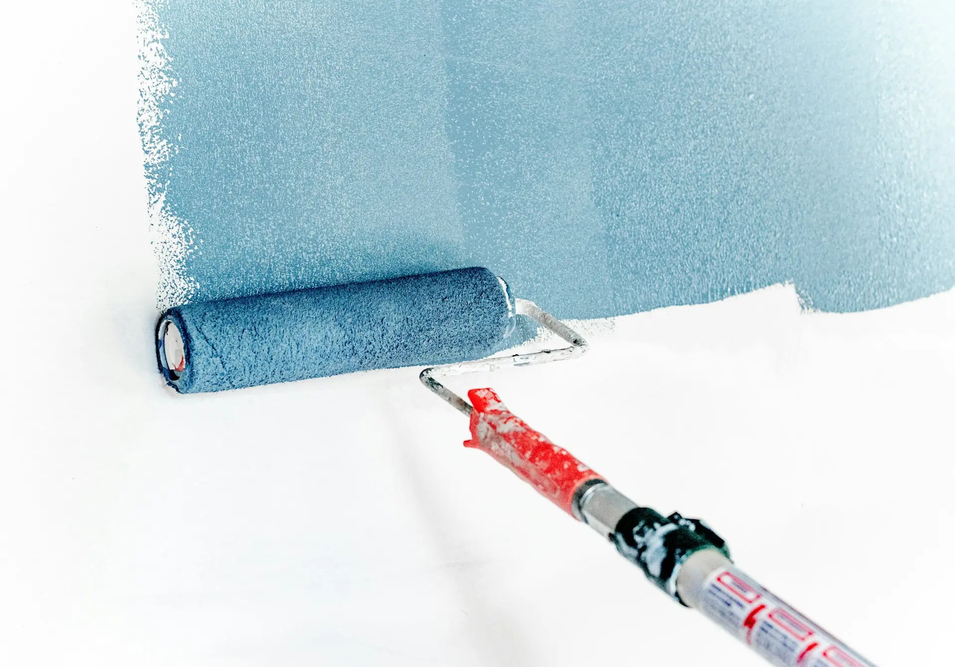 Un rodillo pintando una pared de azul claro