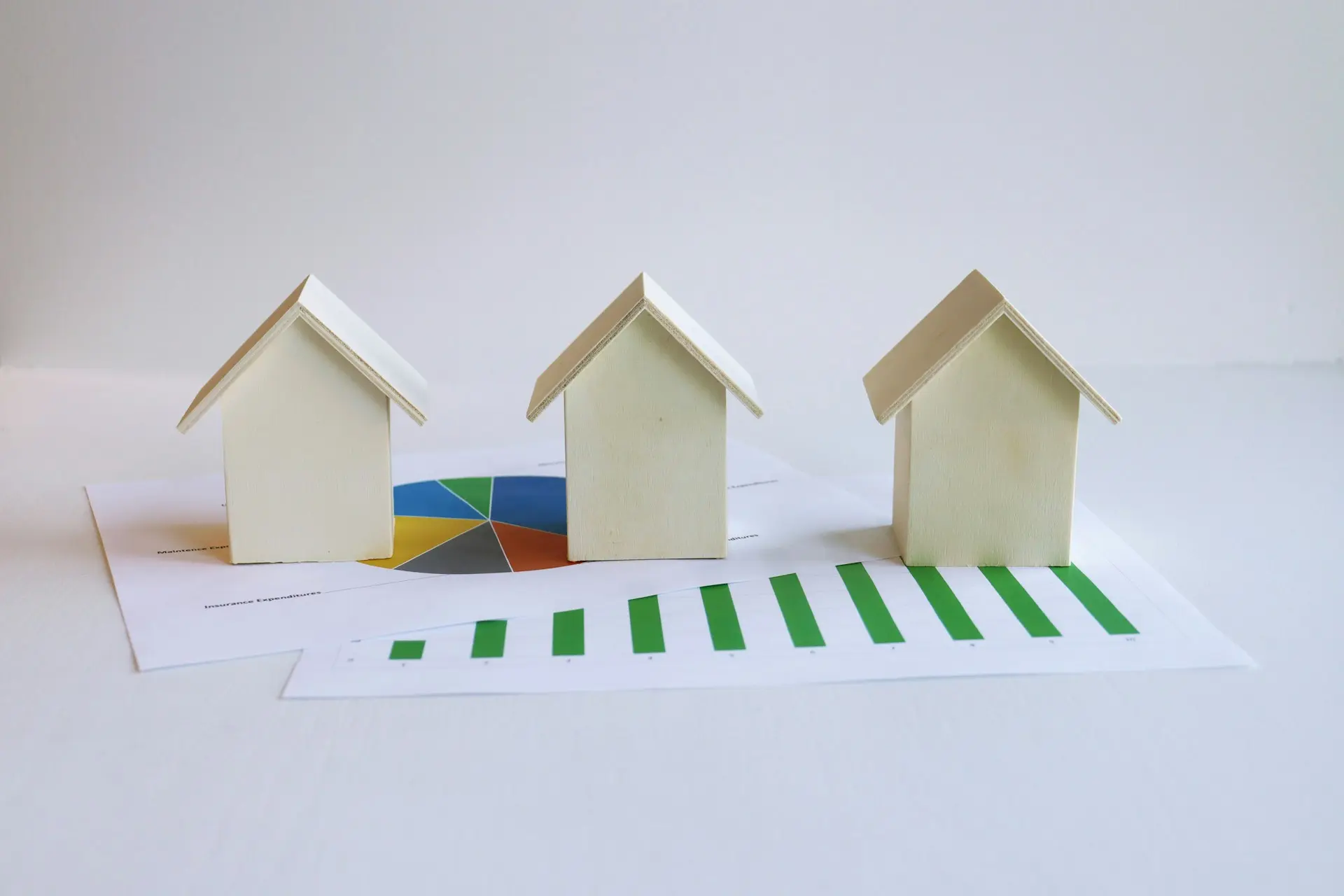 Tres casitas de juguete sobre unas gráficas con barras que suben