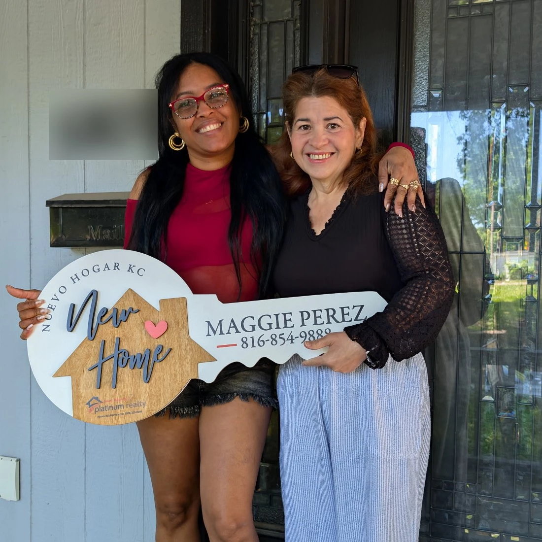 Maggie Perez y una clienta con el letrero de llave de Nuevo Hogar KC en la puerta de su casa